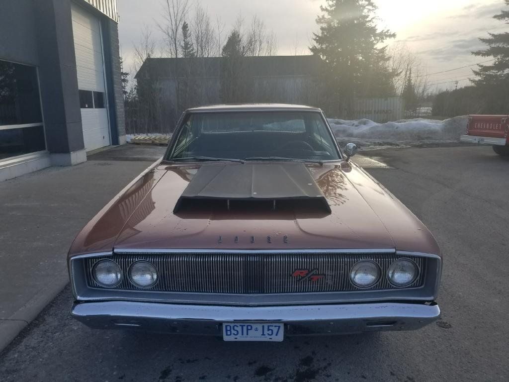 A brown dodge charger with a hood scoop is parked in a parking lot.