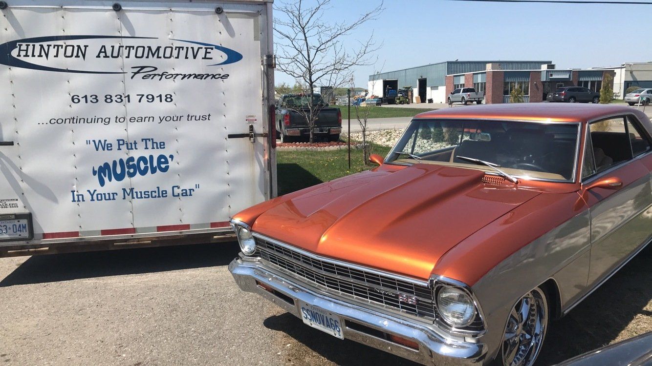 A car is parked next to a trailer that says hinton automotive
