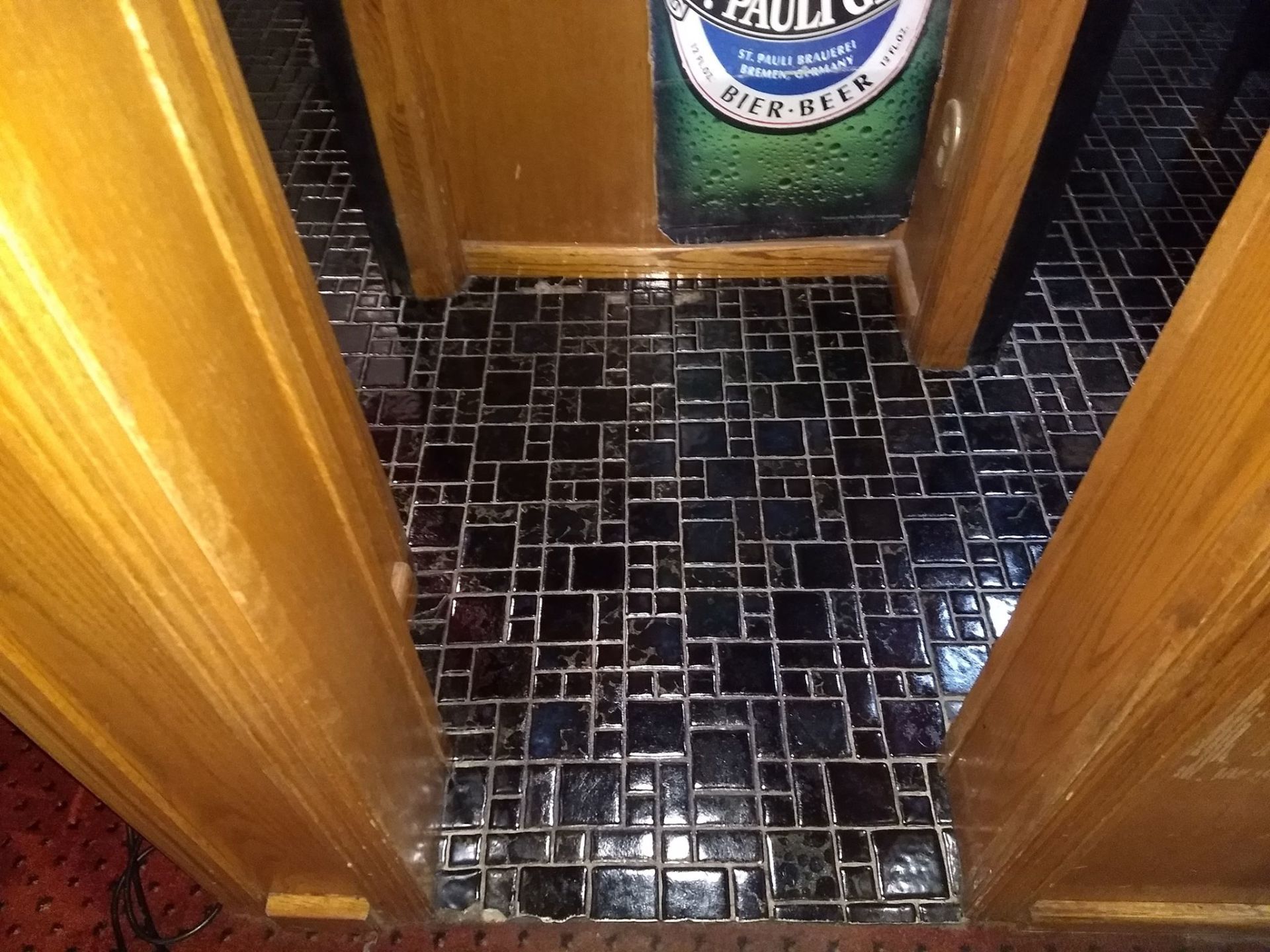 A bottle of heineken beer is hanging on a wall