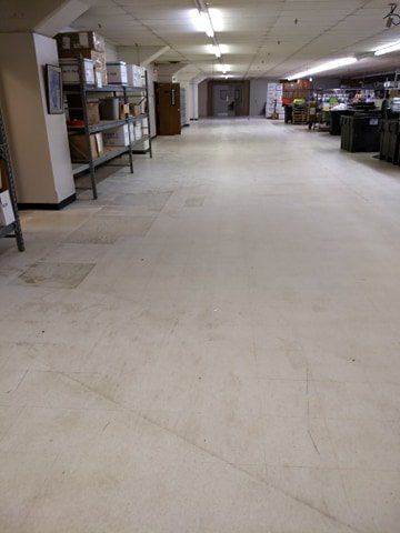 A large empty room with a white floor and shelves.