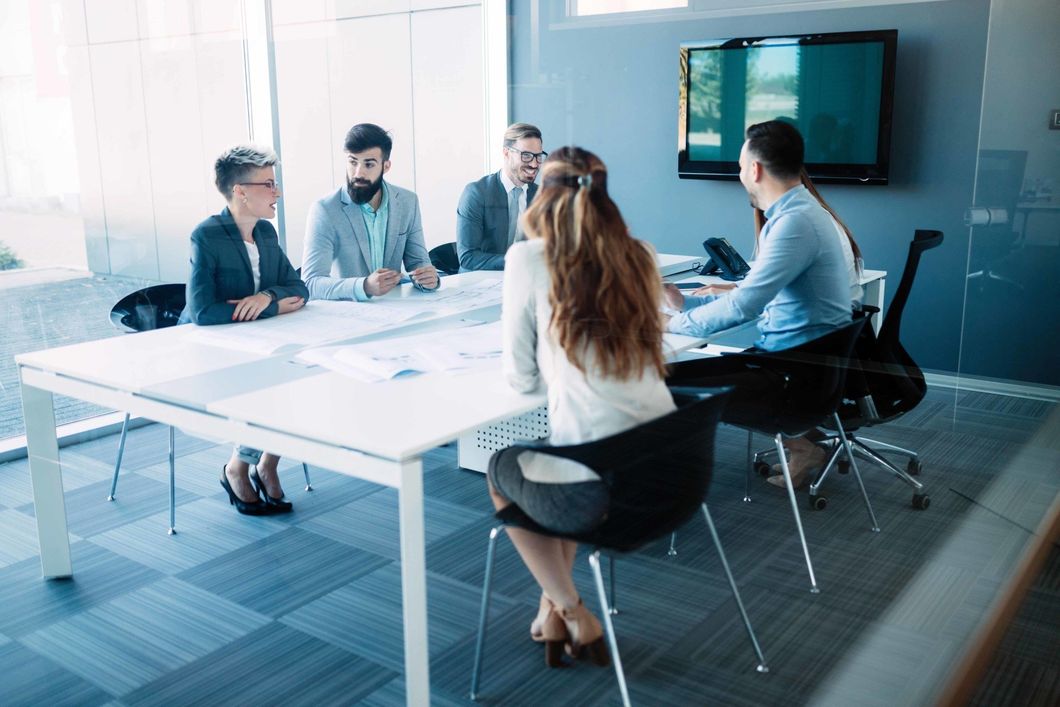 A group of people are sitting around a table in a conference room having a meeting.