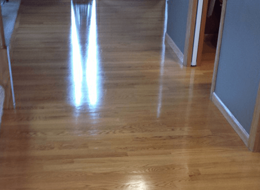 A hallway with a wooden floor and a reflection of light on it.