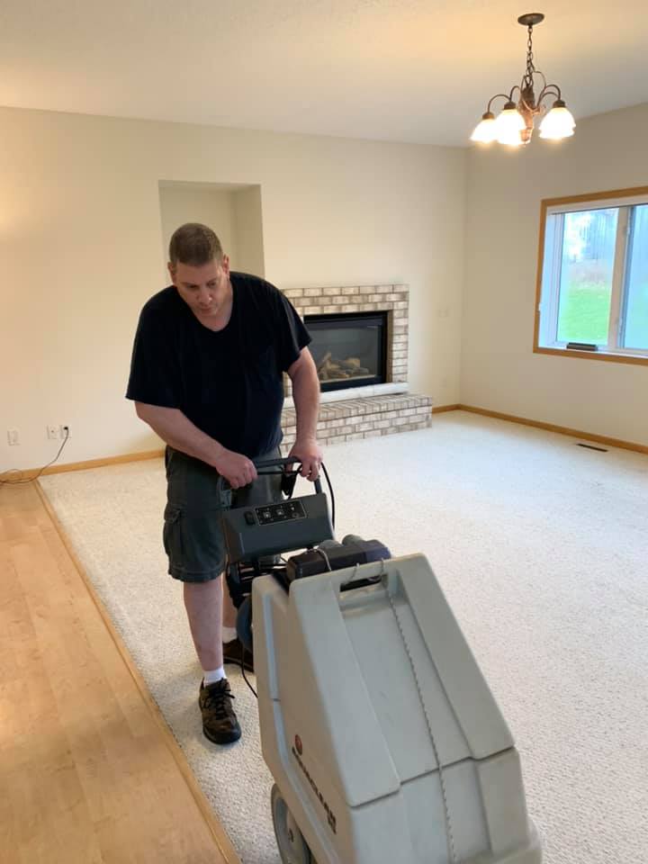 A man is using a vacuum cleaner to clean a carpet in a living room.