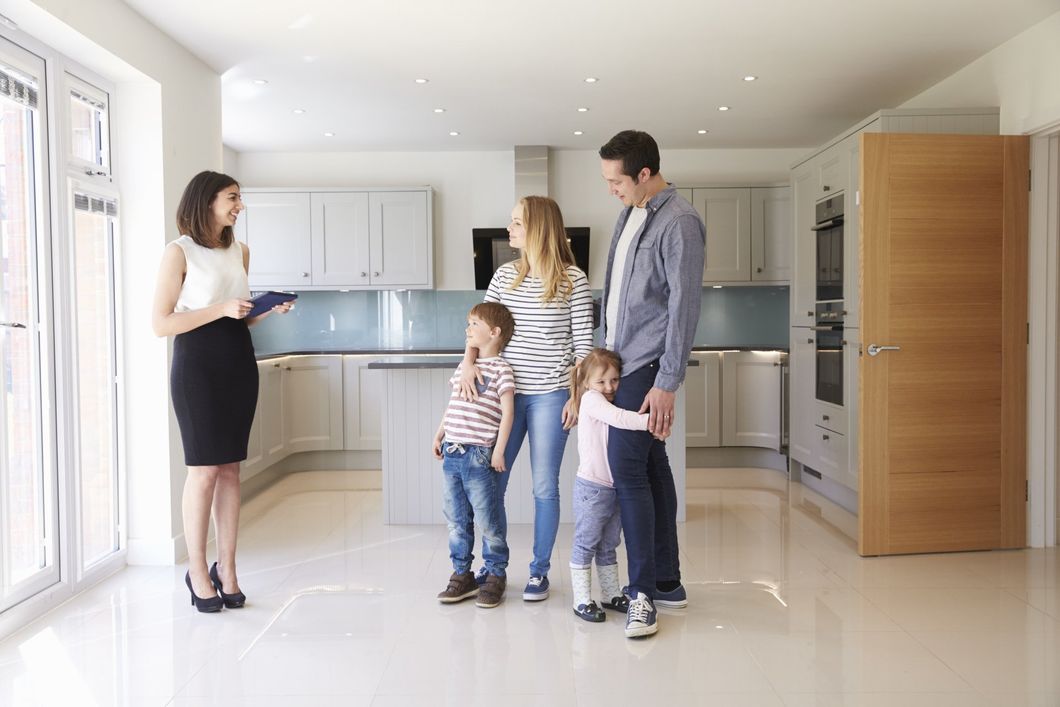 A family is standing in a kitchen with a real estate agent.
