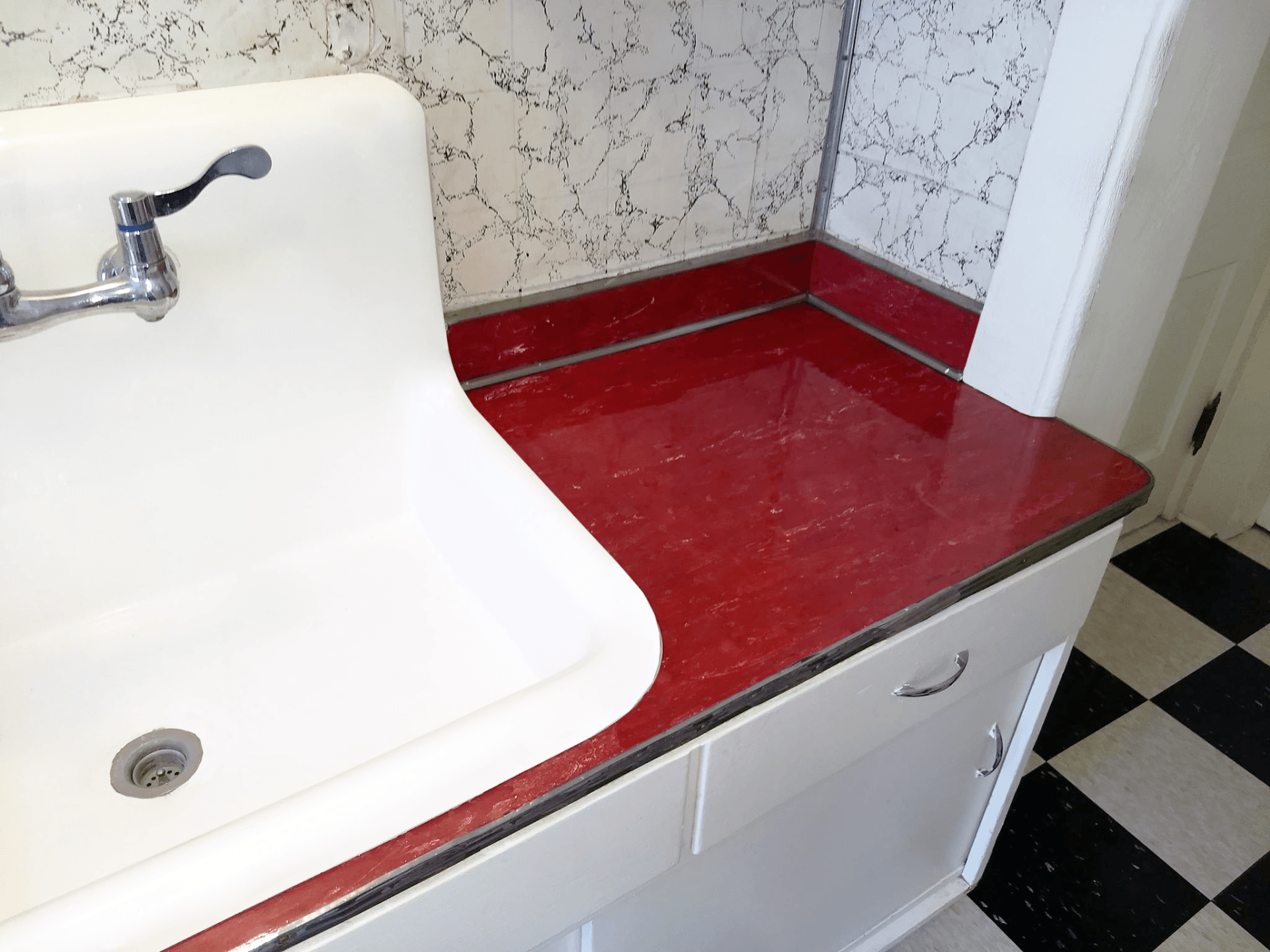 A kitchen sink with a red counter top