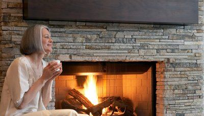 woman sitting  by stone fireplace