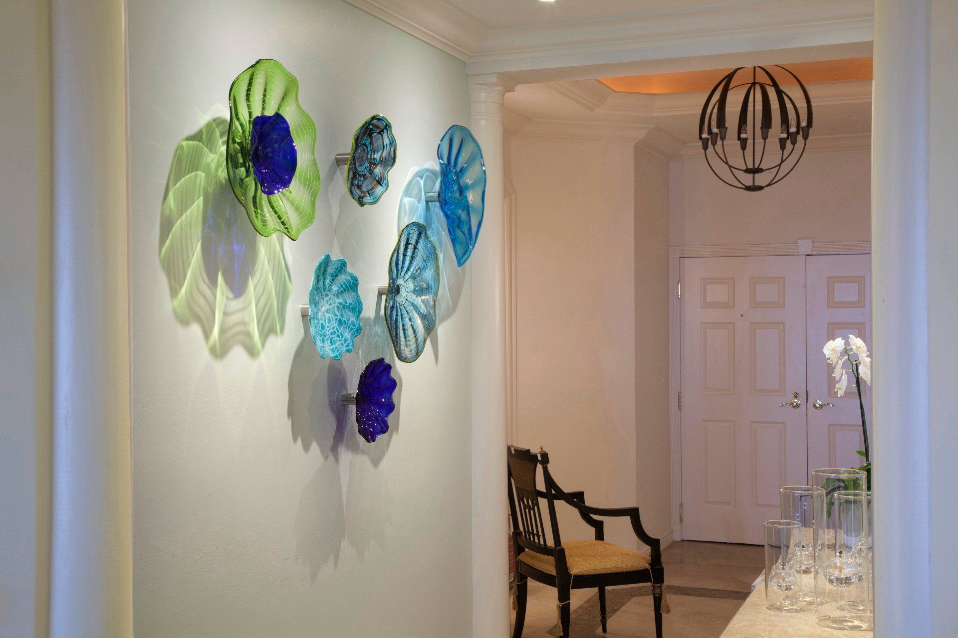 Hallway with blue and green wall flowers, a chair, and a front door in the background