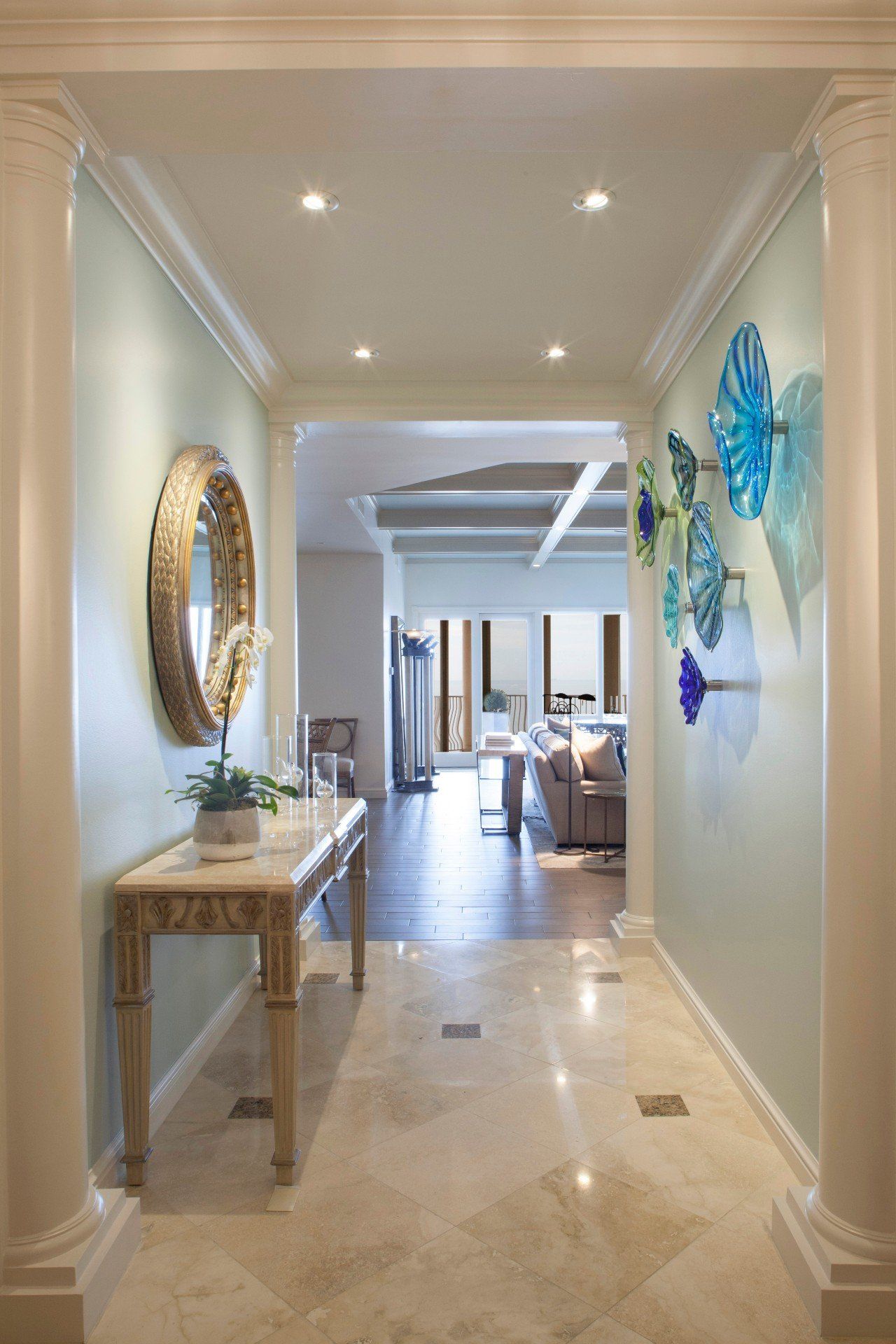 Bright hallway with beige tile, a console table and mirror on the left, and blue wall art on the right.
