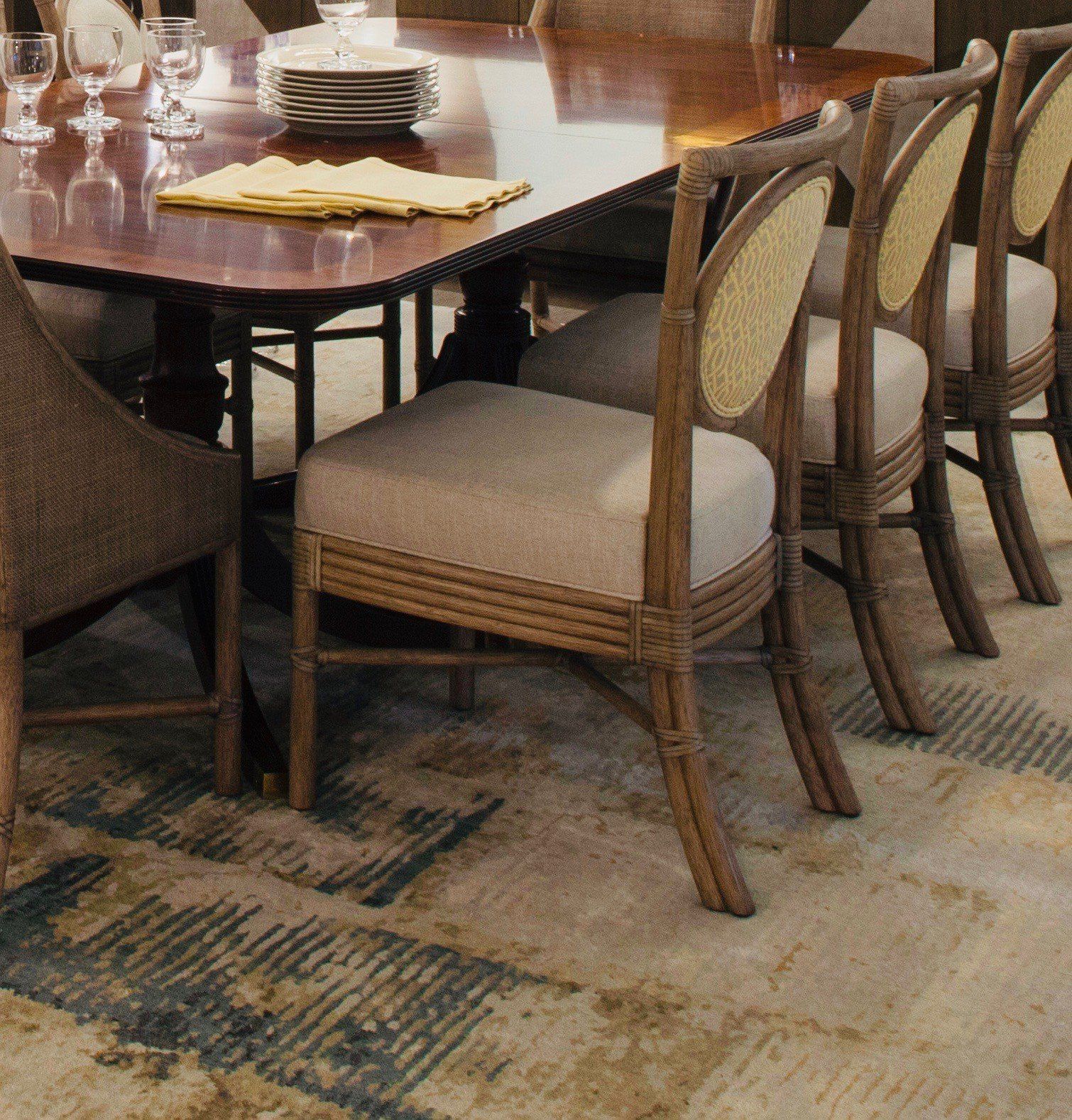 Dining table with beige upholstered chairs on a patterned carpet indoors
