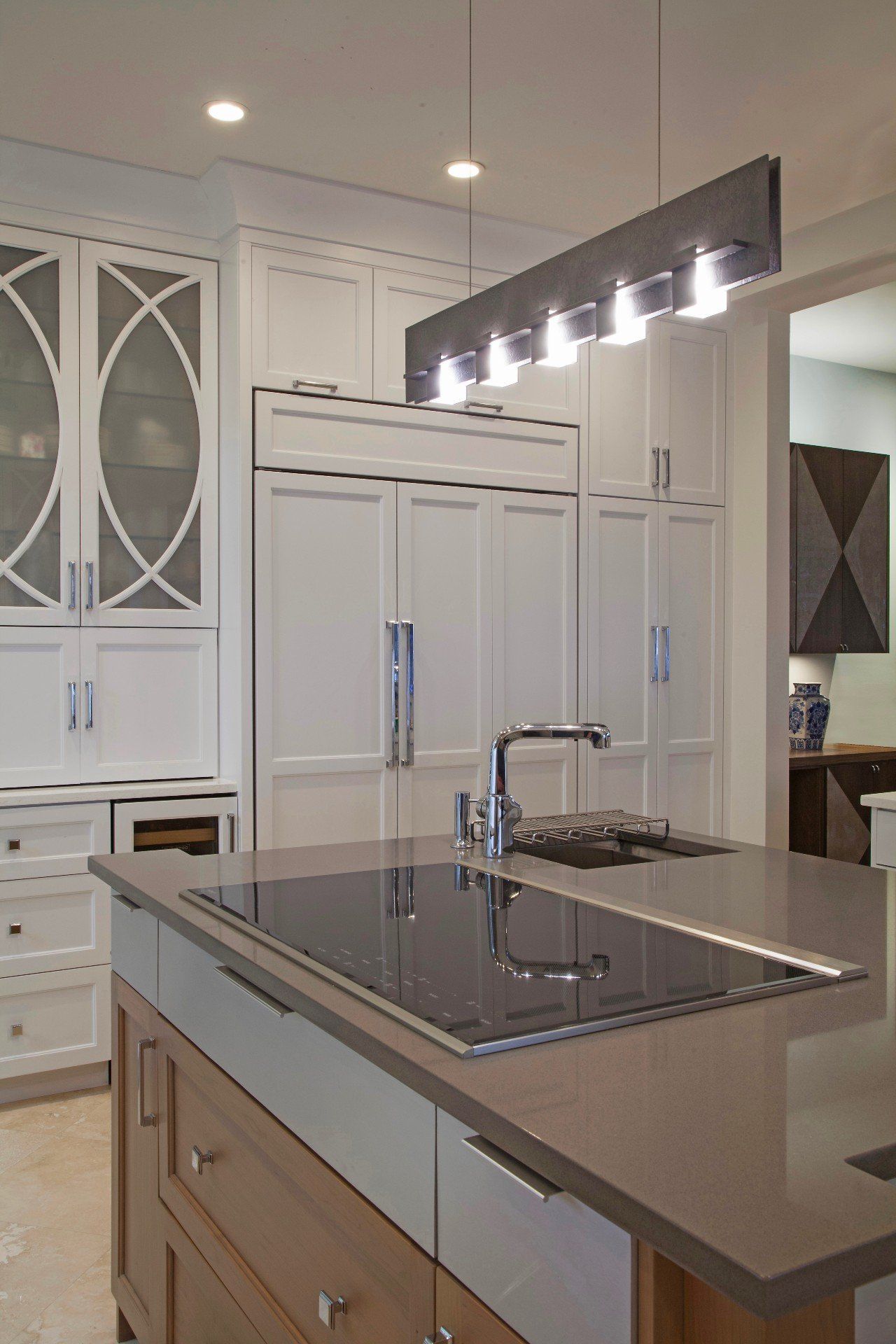 Modern white kitchen with large island, stainless sink, and pendant lighting