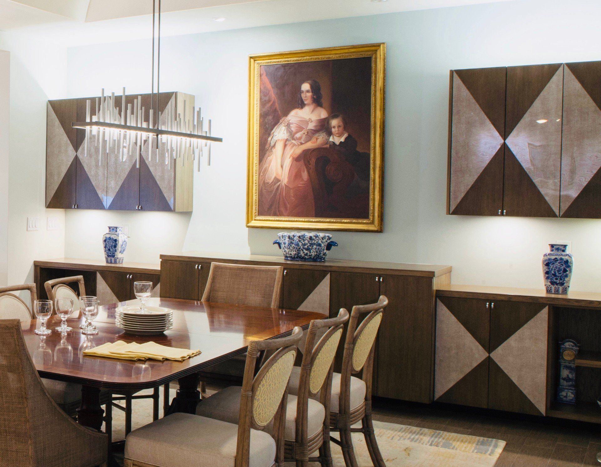 Formal dining room with framed portrait, wood table, and geometric wall art in warm neutral tones