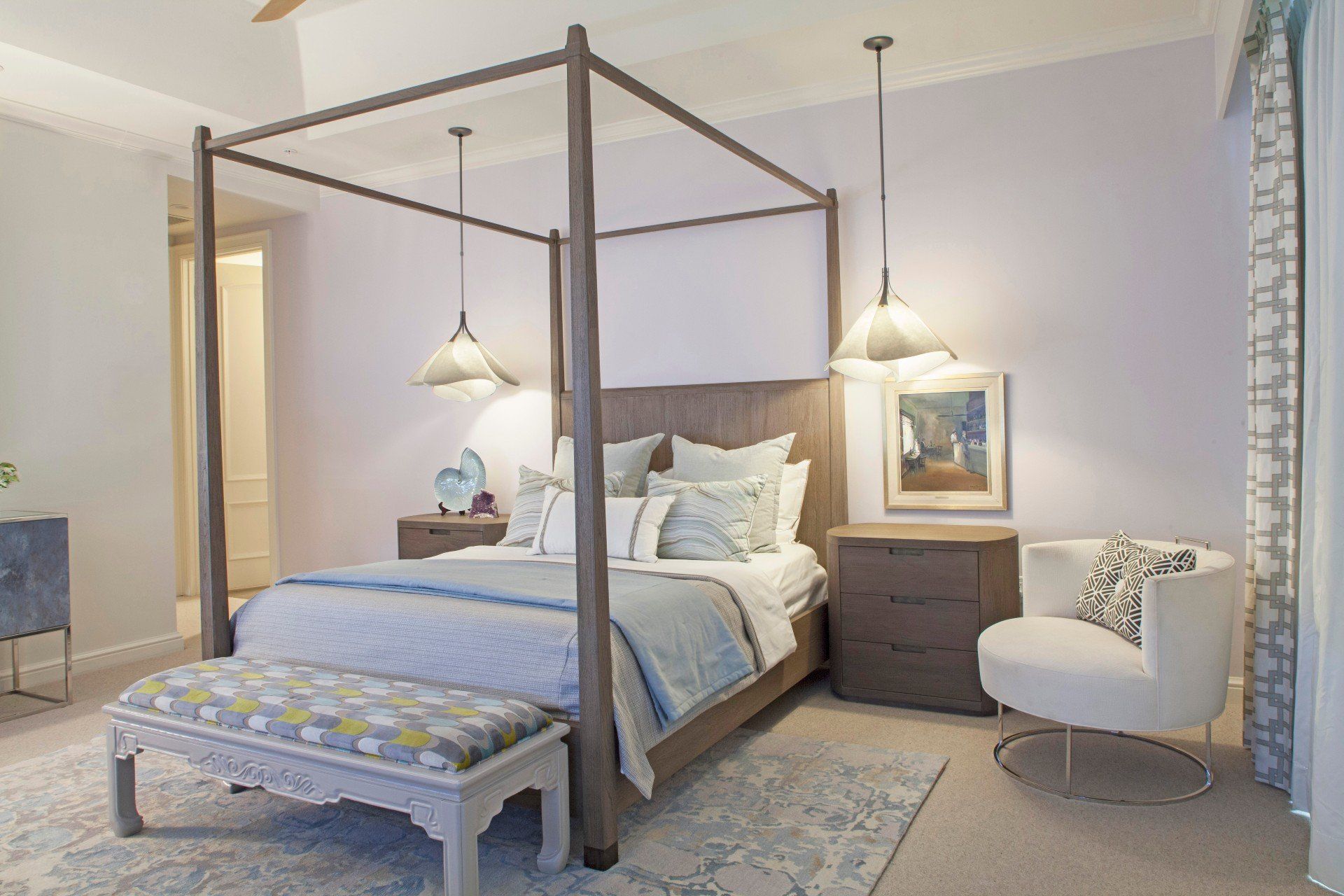 Bright bedroom with four-poster bed, white chair, hanging lamps, and soft blue decor