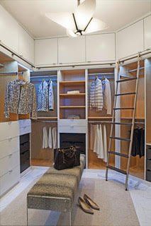 Spacious walk-in closet with white shelves, hanging clothes, a ladder, bench, and full-length mirror