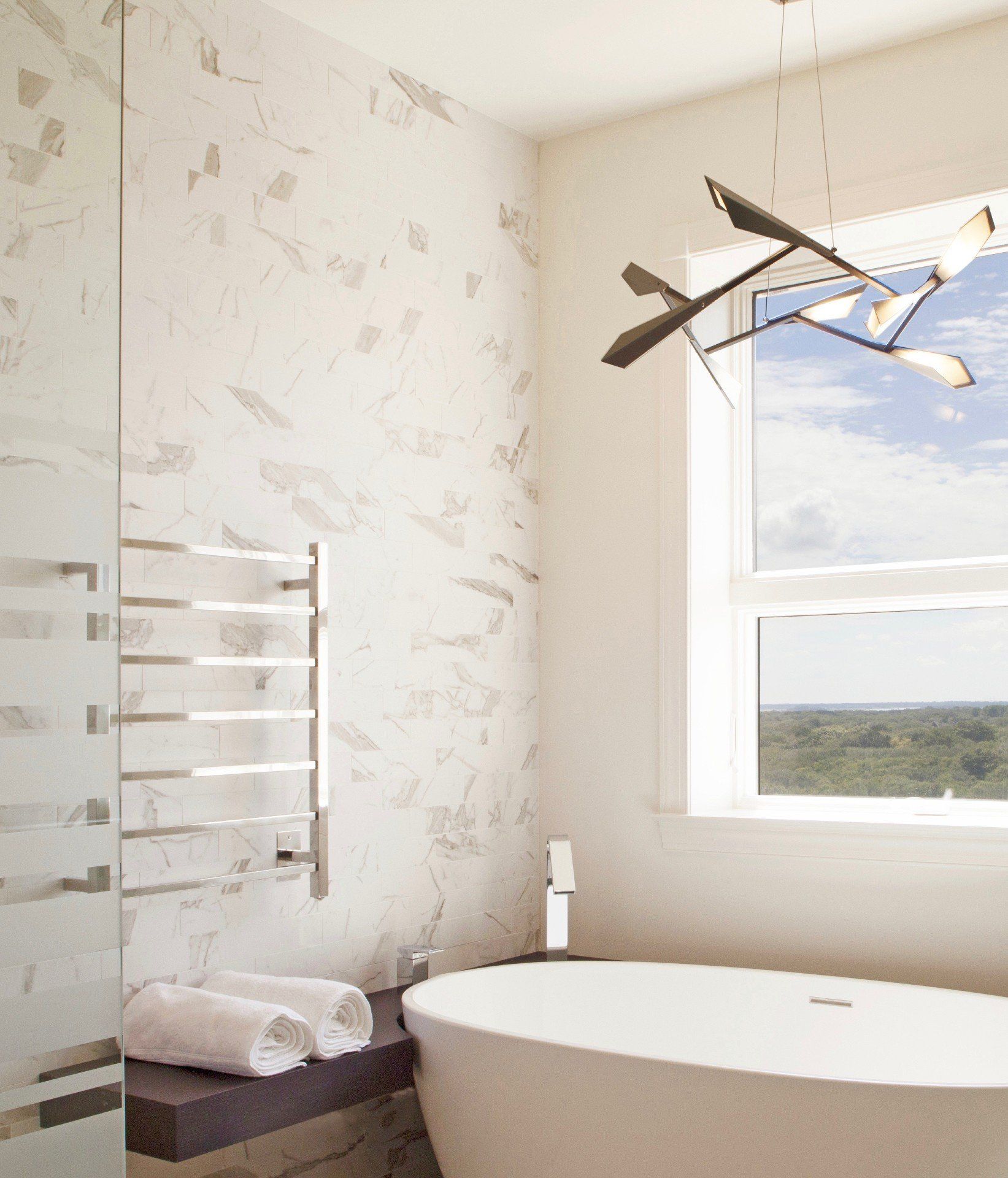 Bright bathroom with a freestanding tub, window view, towel rack, and modern ceiling fan
