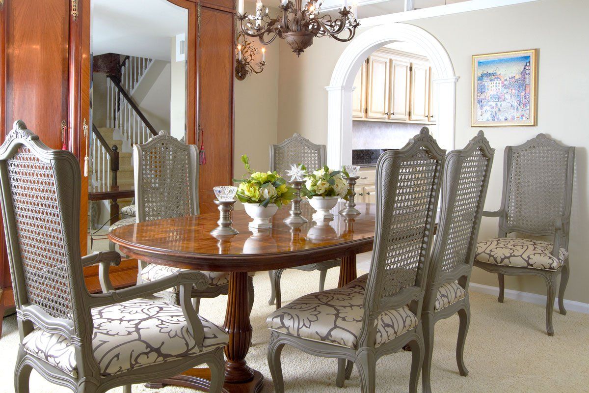 Elegant dining room with round wooden table, patterned chairs, and decorative mirror