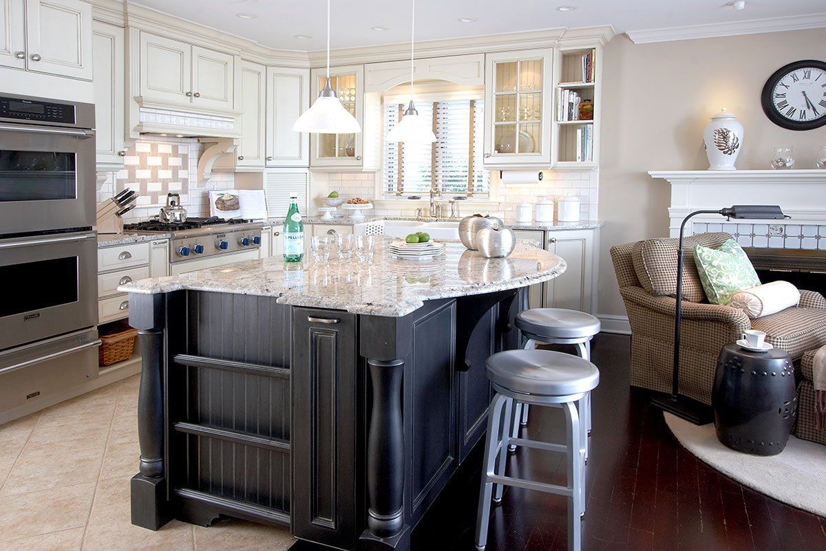 Bright modern kitchen with a dark island, white cabinets, and bar stools by a window.