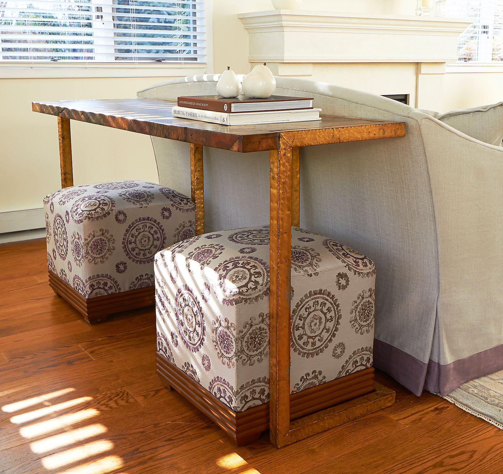 Wooden table with patterned ottomans beside a couch in a bright room