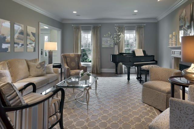 Elegant gray living room with piano, sofa, armchairs, and patterned rug by large windows