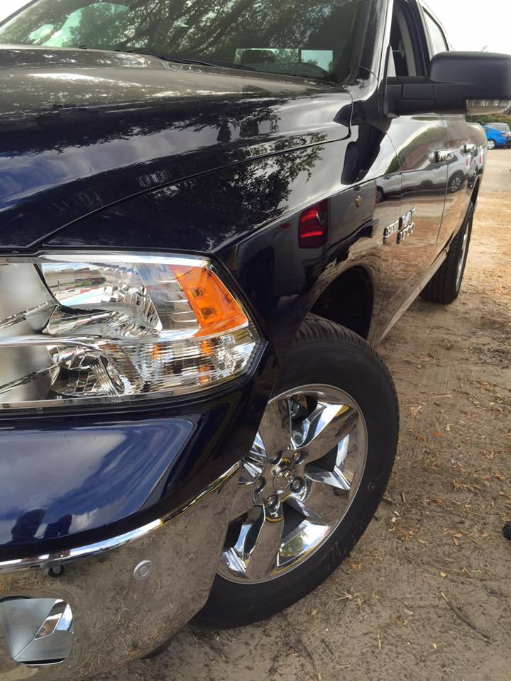 a blue dodge ram truck is parked in the dirt