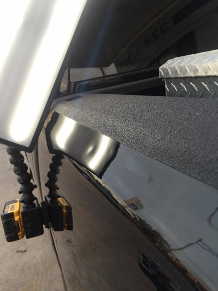 a close up of a black truck with a yellow light attached to it