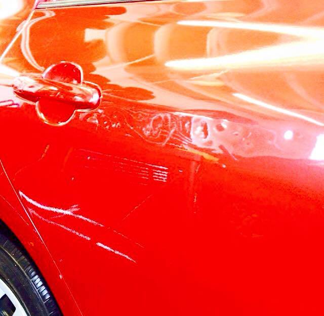 a close up of a red car with a scratch on the door .
