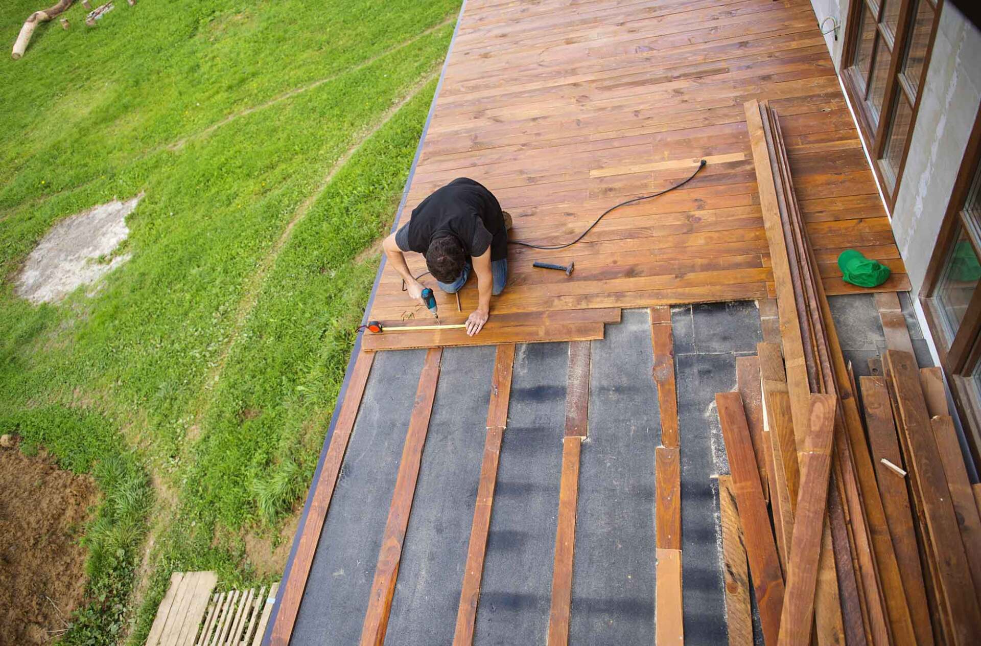 A man is working on a wooden deck — Building Services in Rockhampton
