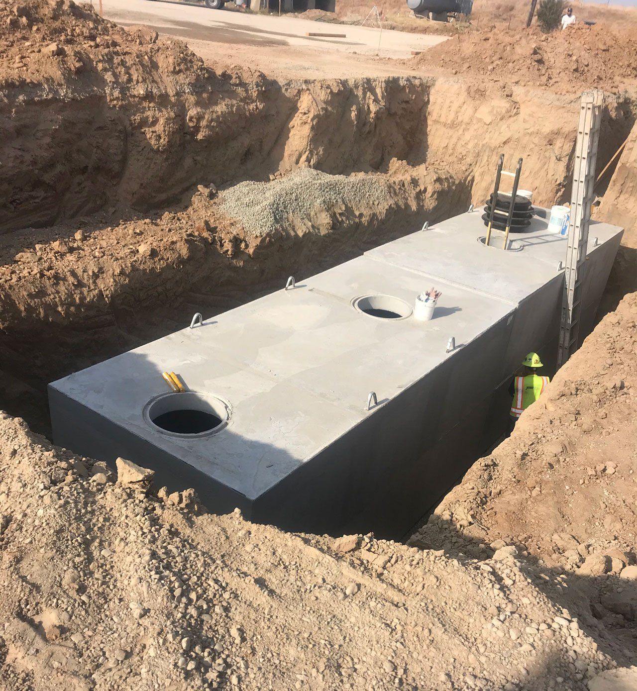 Concrete tank in an excavated trench, prepared for underground installation.