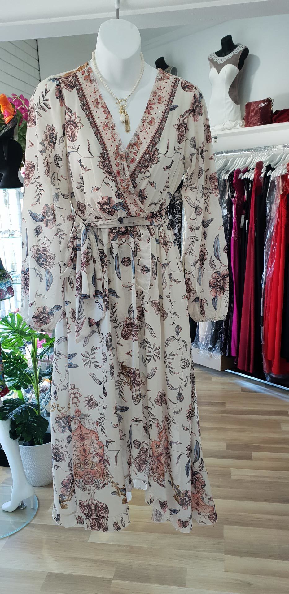 Mannequin in a floral wrap dress, with a tan and brown pattern. Retail store setting.