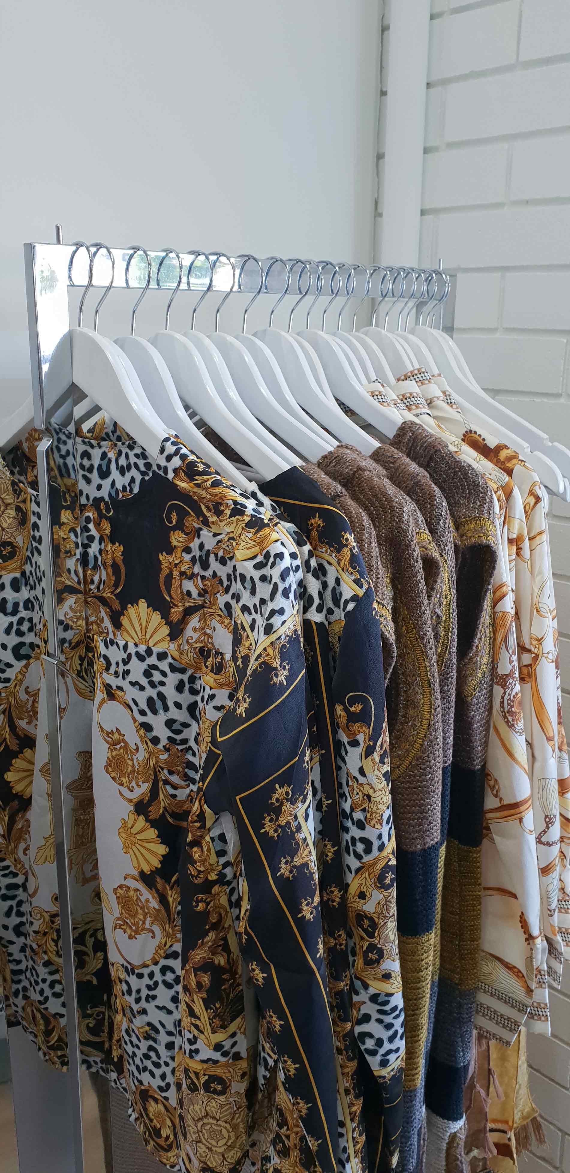 Clothing rack displaying various patterned long-sleeve dresses.