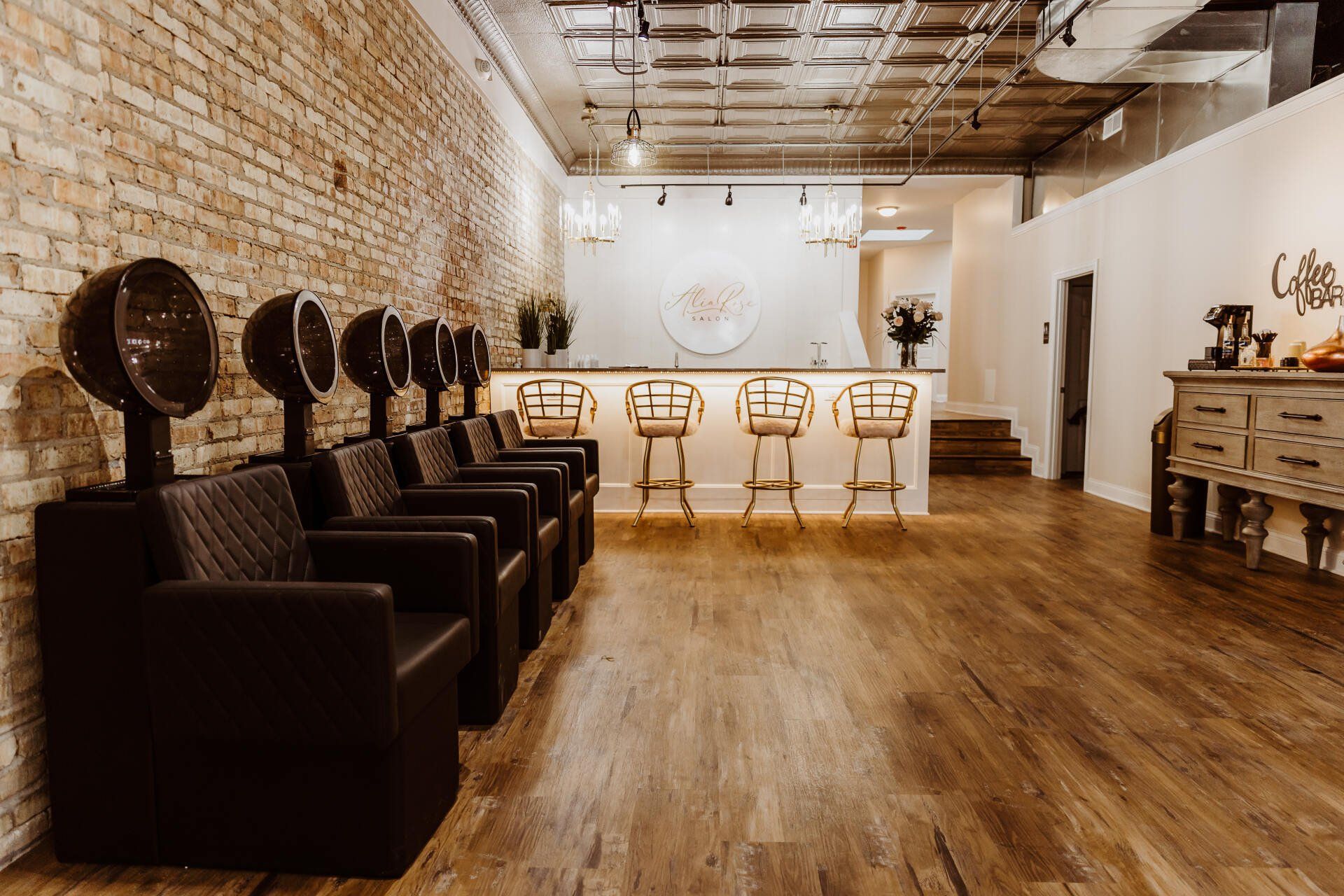 Hair salon interior with brick wall, brown chairs, and bar with stools.