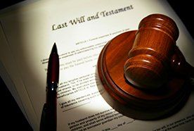 Wooden hammer and gavel, and a pen, on top of a will document