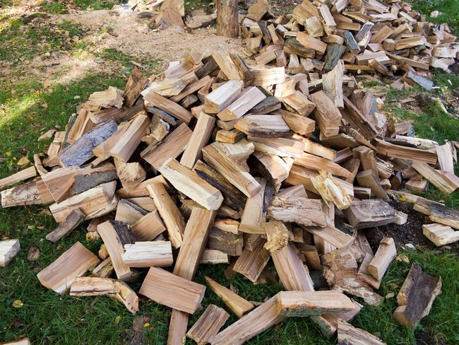A pile of chopped wood is sitting on the grass.