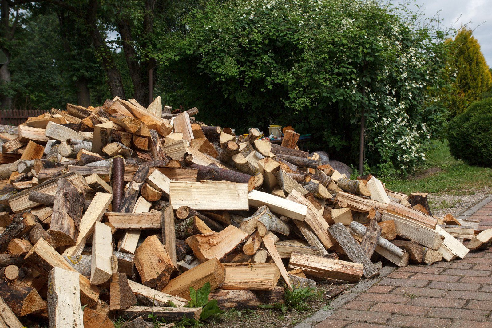 A pile of wood is sitting on a brick sidewalk.