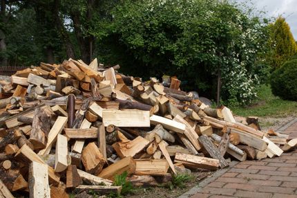 A pile of wood is sitting on a brick sidewalk.