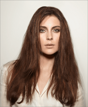 A woman with long brown hair is wearing a white shirt