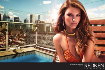 A woman in a bikini is sitting on a bench next to a pool.