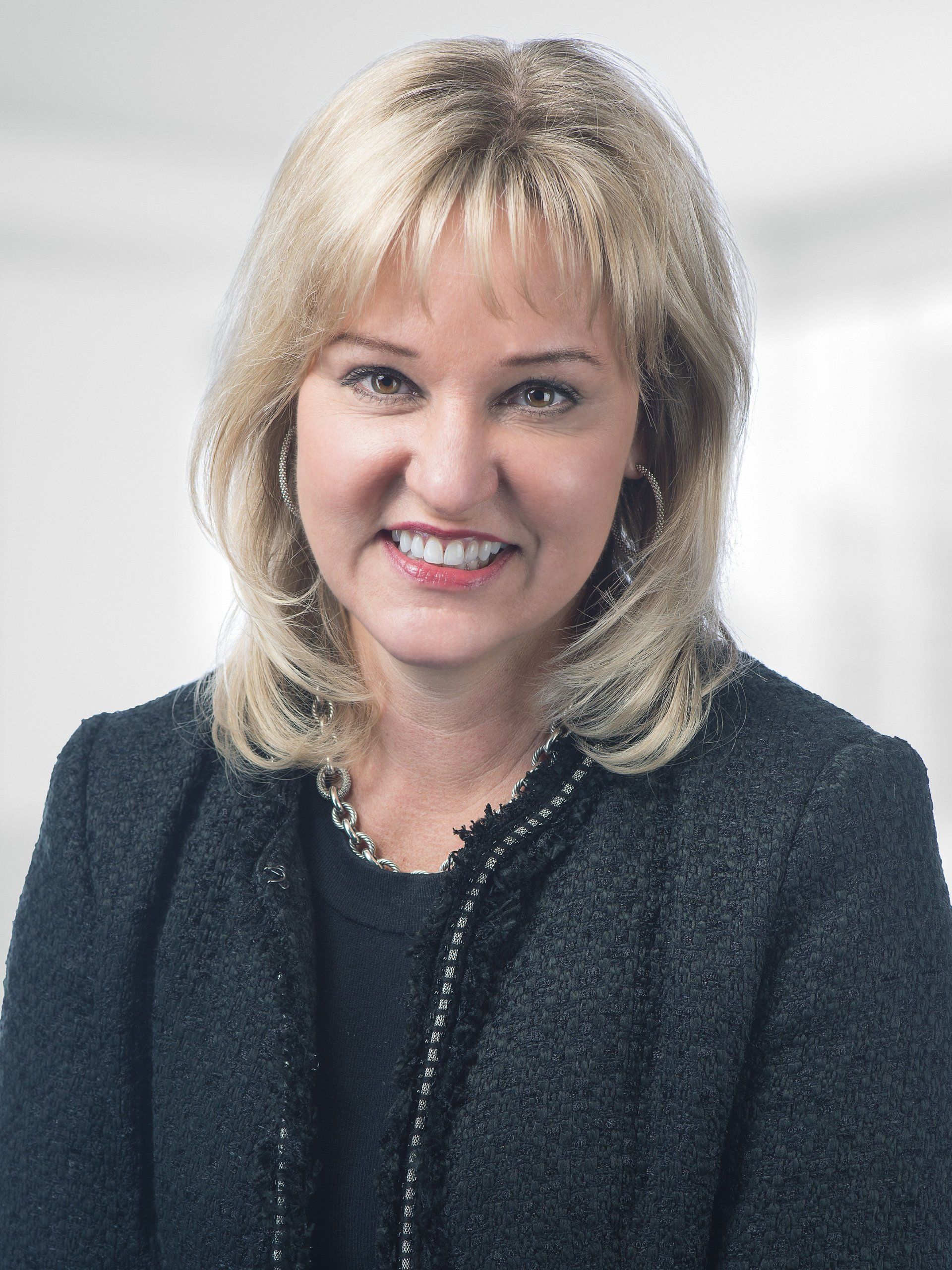 A woman is wearing a black jacket and smiling for the camera.
