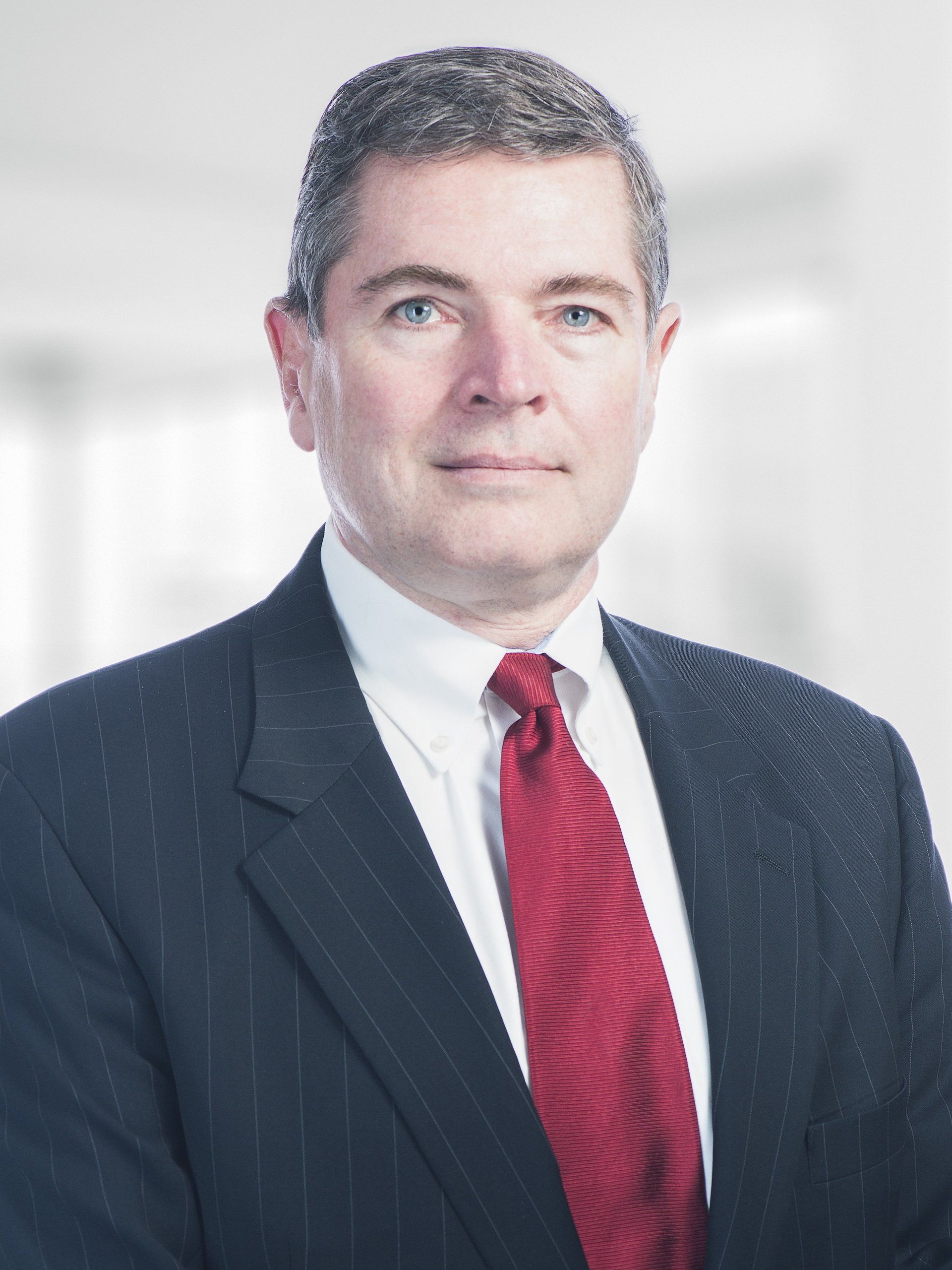 A man in a suit and tie is standing in front of a window