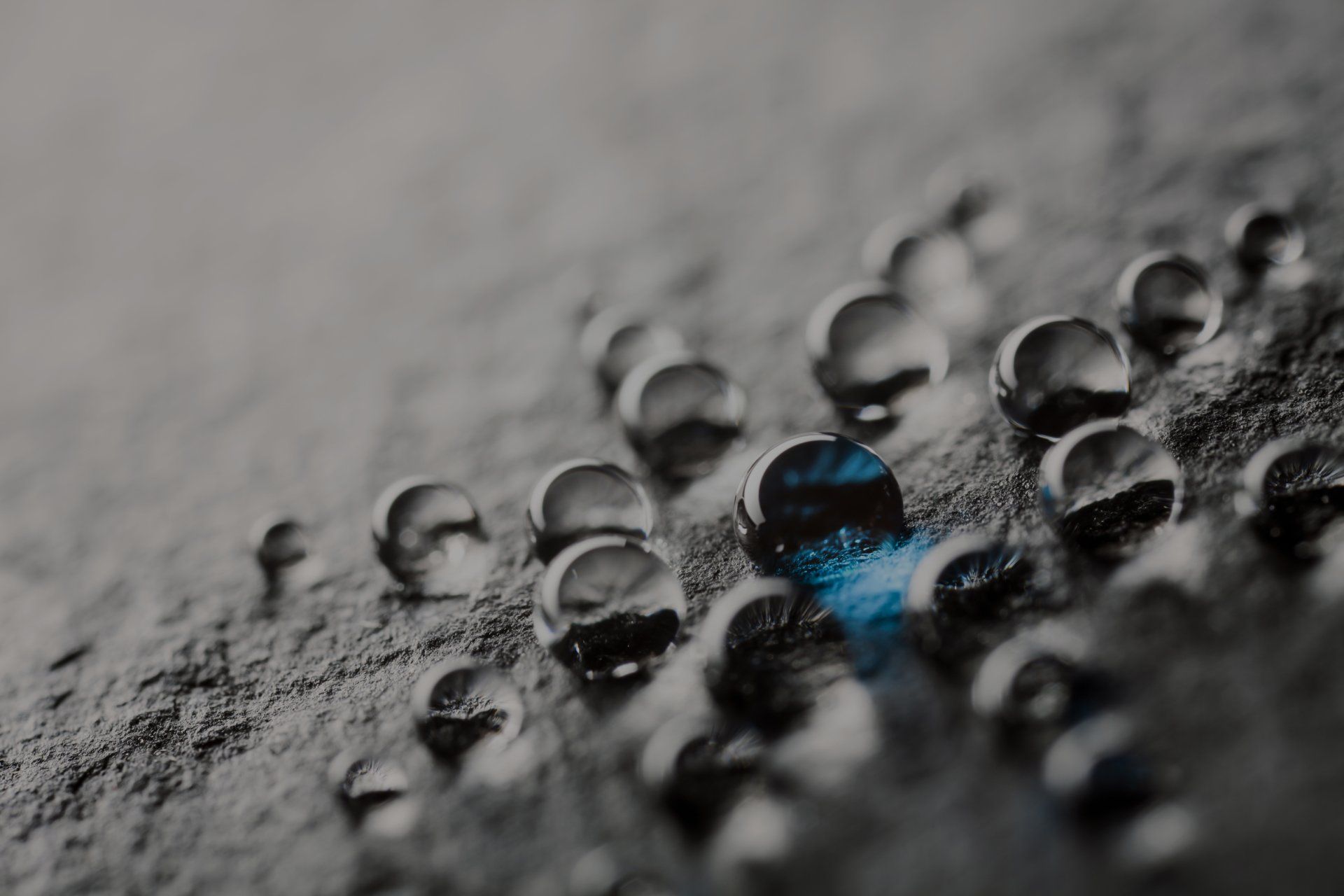 A black and white photo of water beads on a surface.