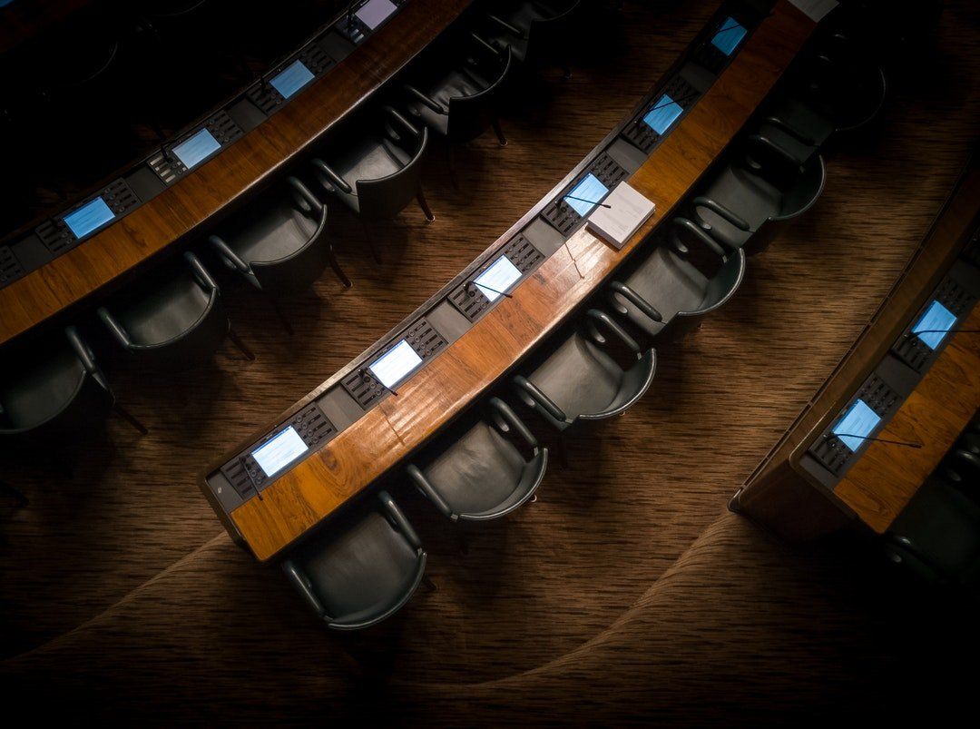 A row of wooden tables and chairs in a dark room.