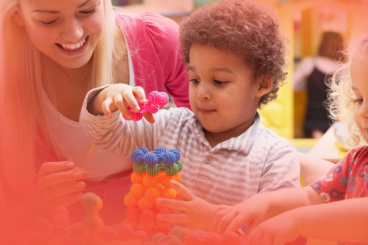 A woman and two children are playing with toys in a room.