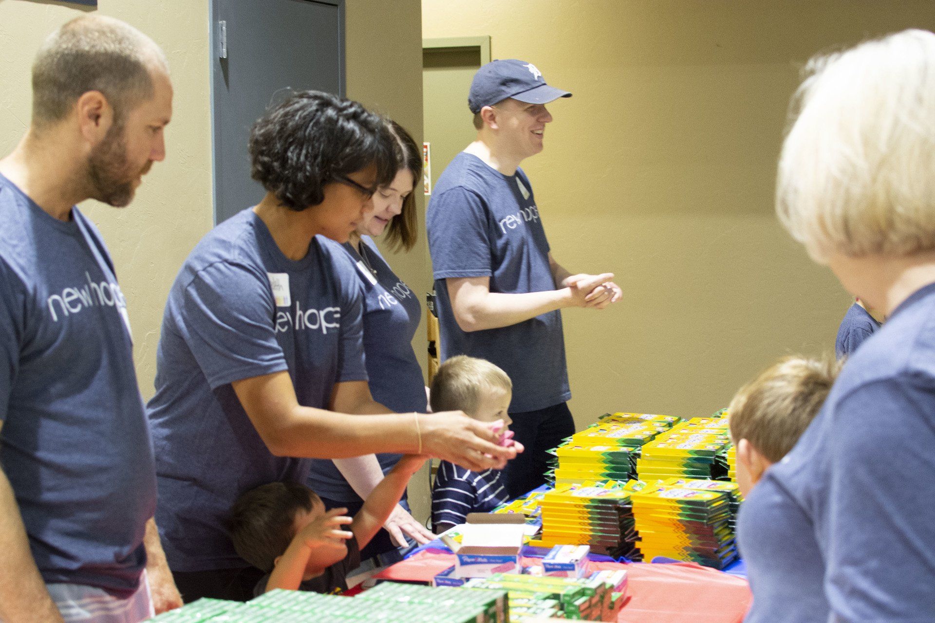 A group of people in blue shirts are standing around a table.