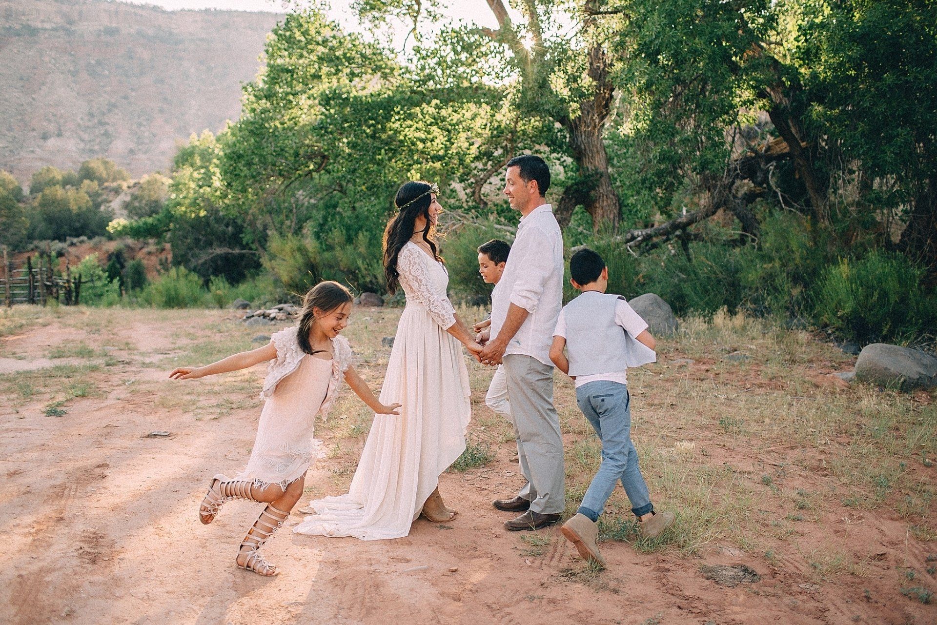 Family of five in a natural setting, with a couple holding hands, while children run around them.