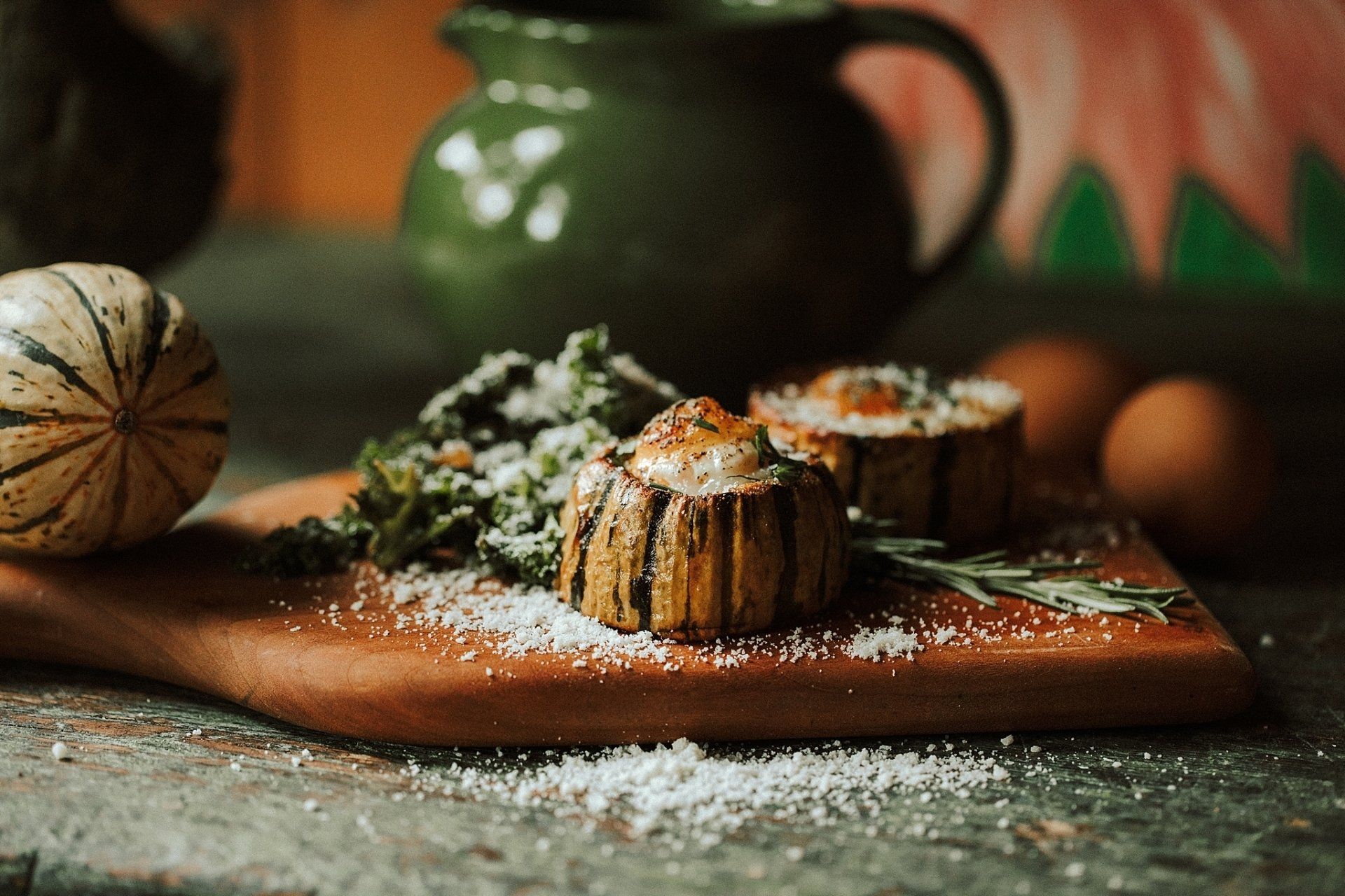 Roasted vegetable dishes on wooden board with squash and jug.