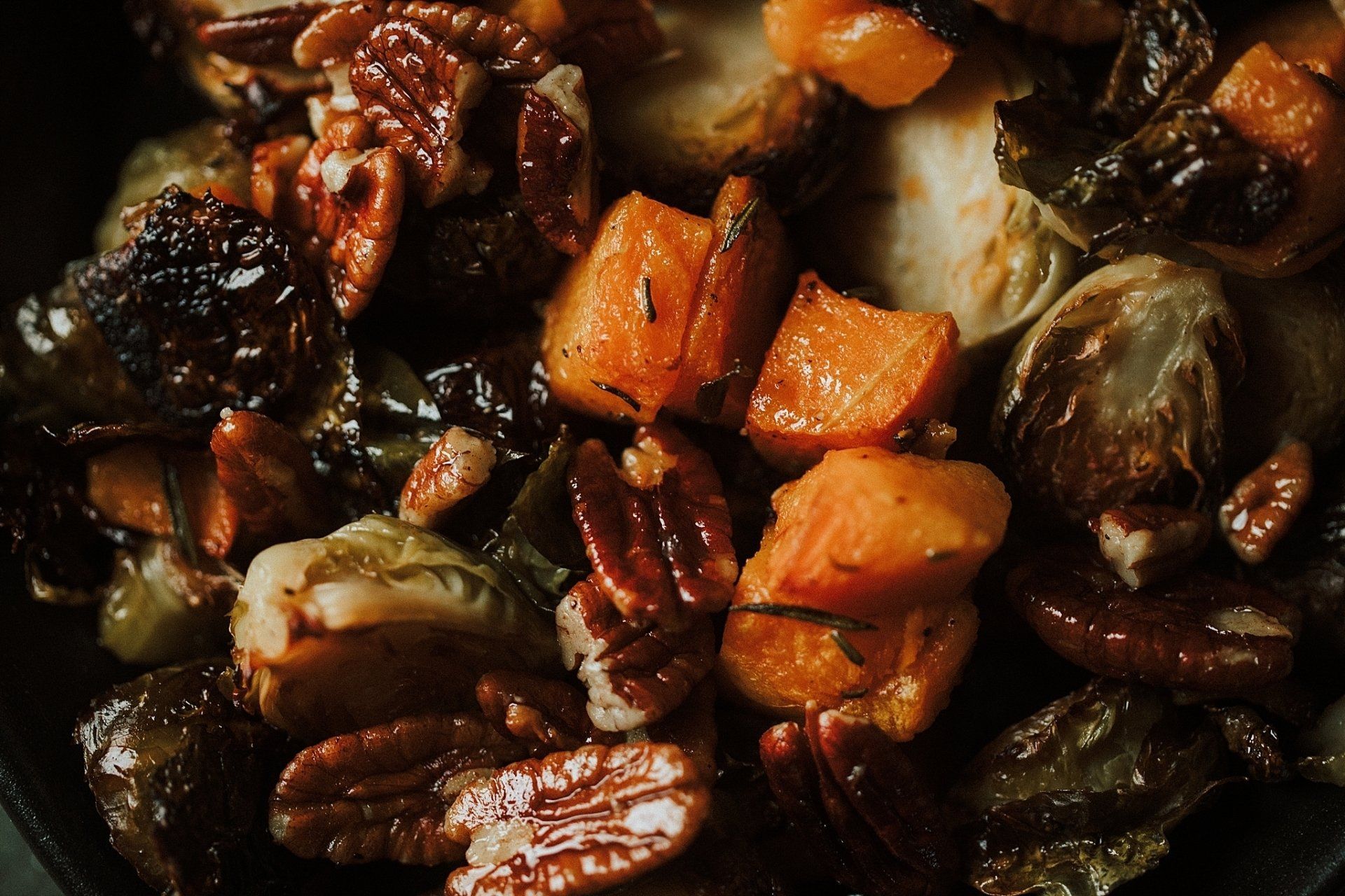 Roasted Brussels sprouts, butternut squash, and pecans in a pan.