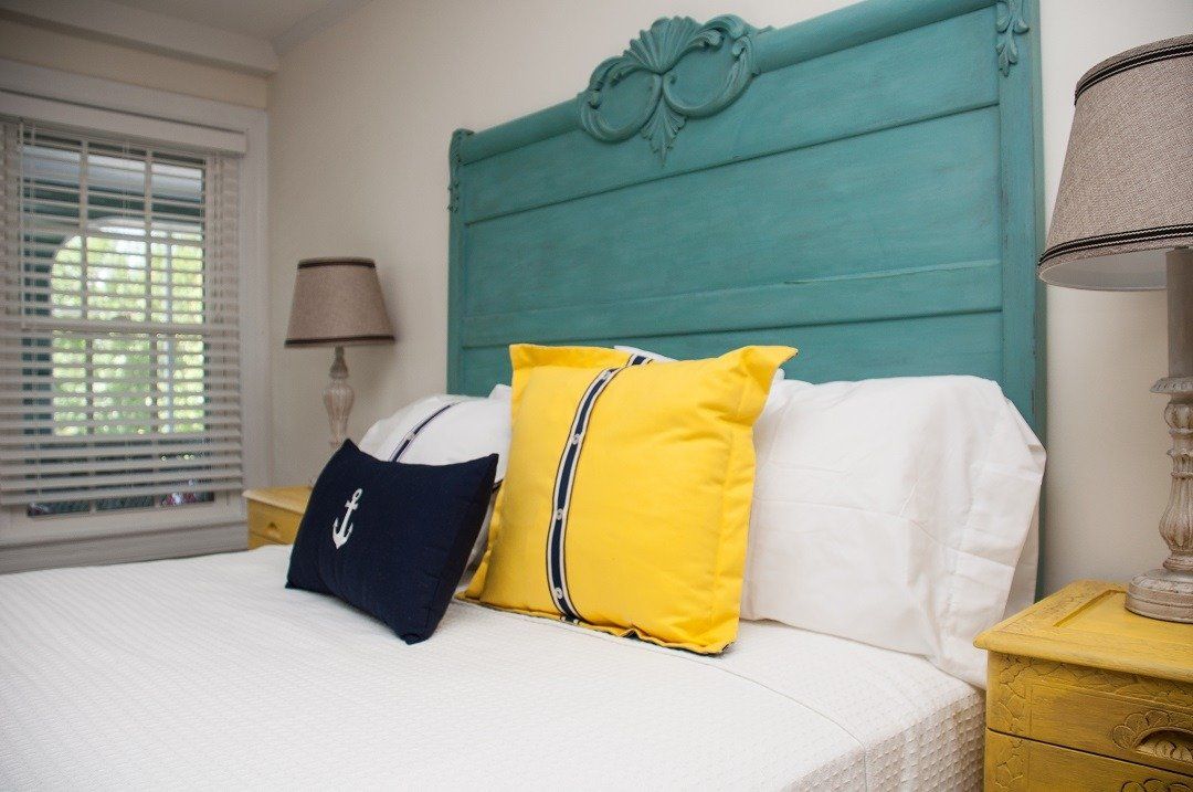 Bedroom, bed and headboard with white bedding and yellow pillows