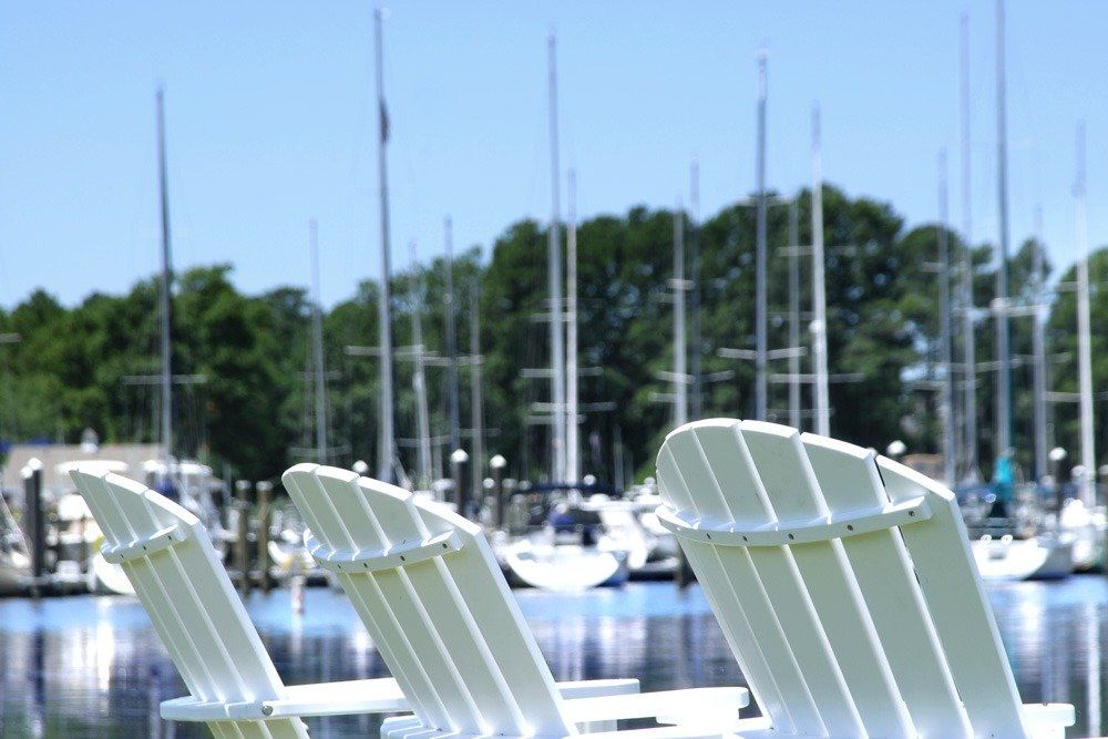 Adirondack chair with sailboats and green trees in the background