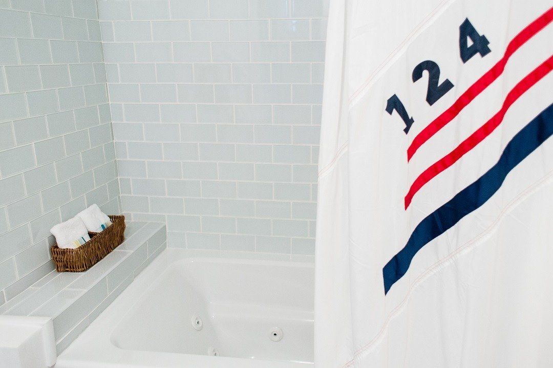 A tiled bath tub with a white shower curtain