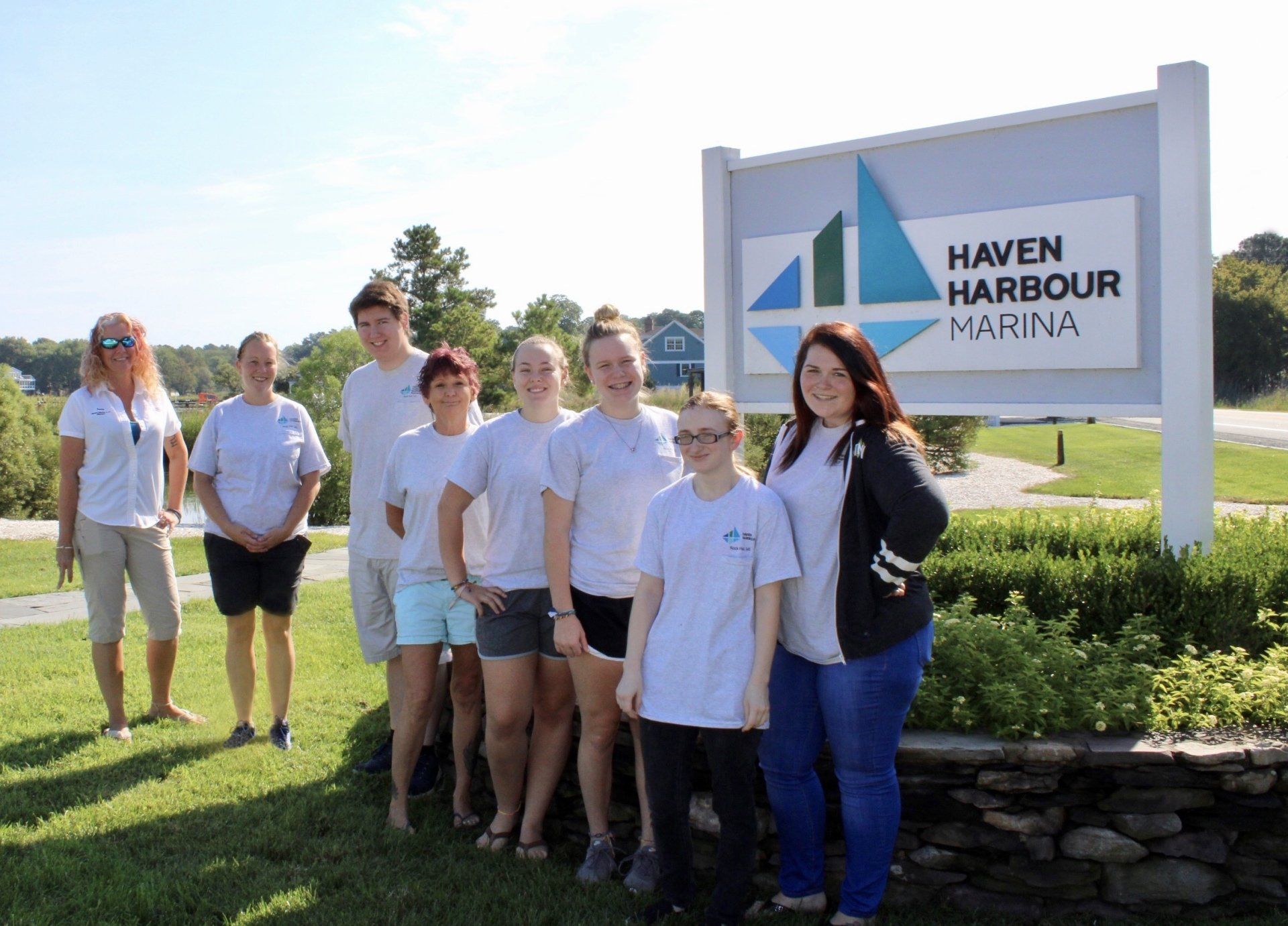 Staff in group photo taken in front of business entrance sign