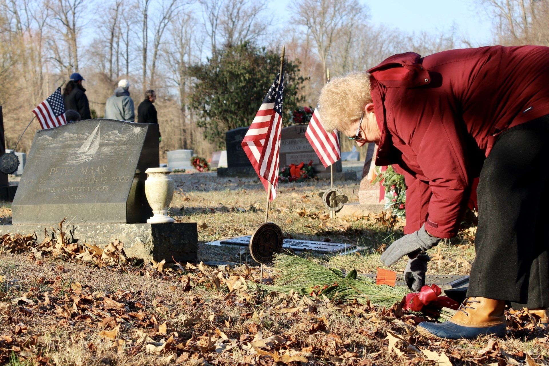 Employee laying wreath at grave of veteran during the holidays